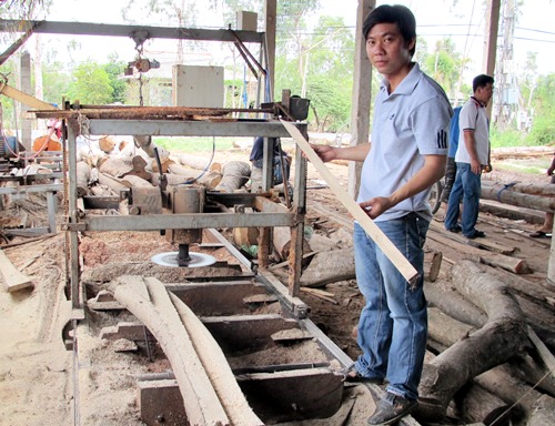 Anh Phạm Hồng Thơm bên cạnh máy cưa dĩa do anh mới sáng chế